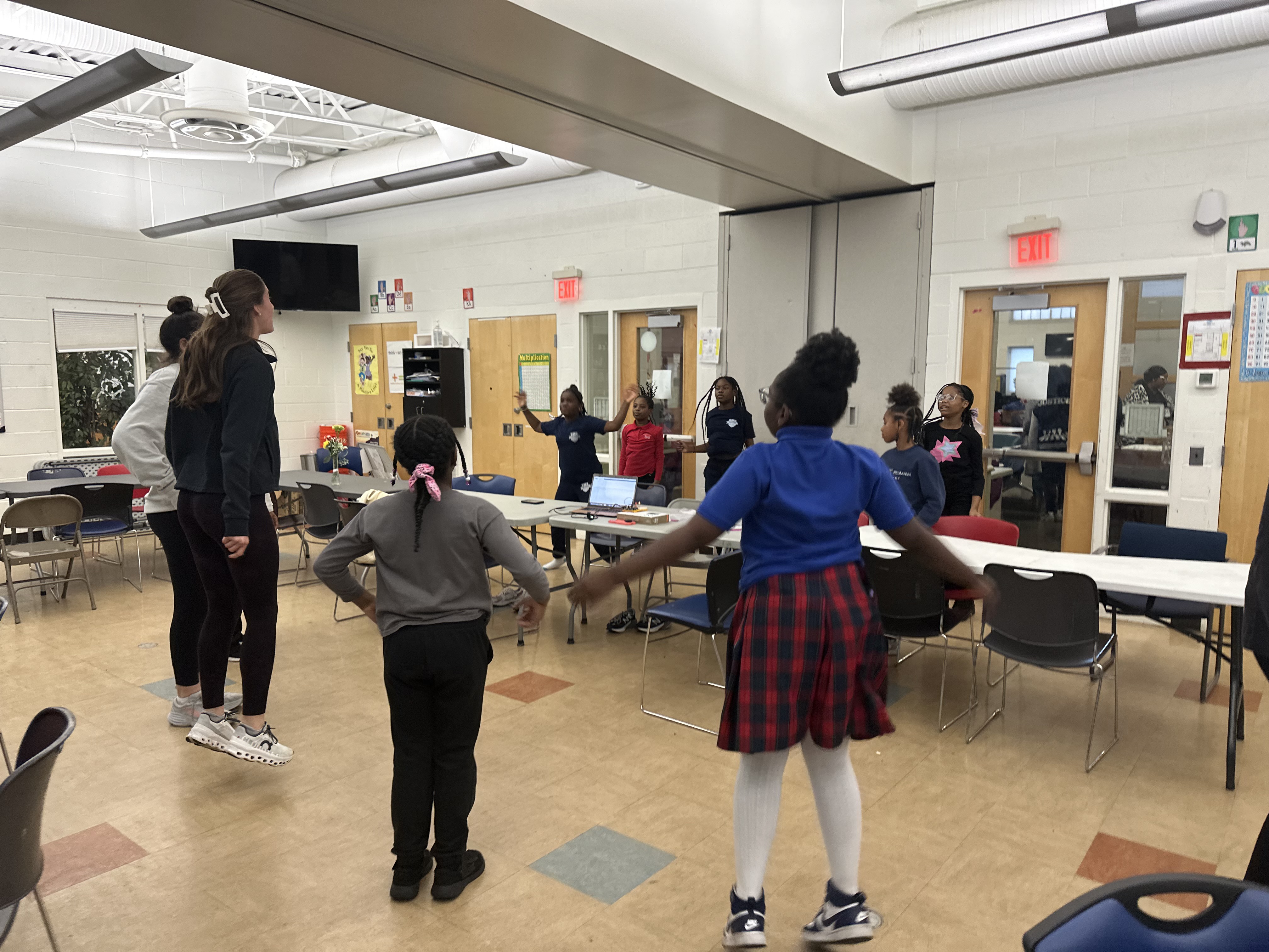 Widener students and grade school children jump up and down during an activity.