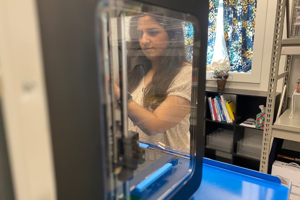 Lydia stands in front of the 3D printer.