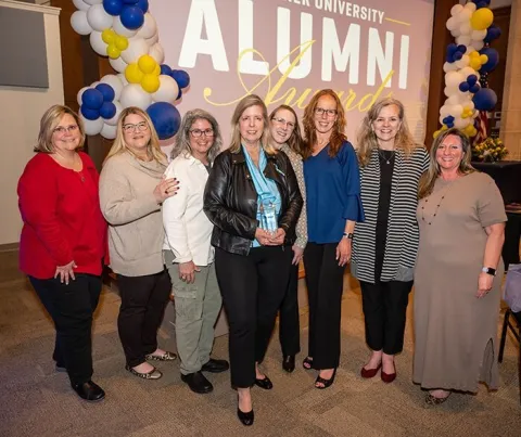 Marcia O'Connor posing with her award and friends at the alumni awards ceremony