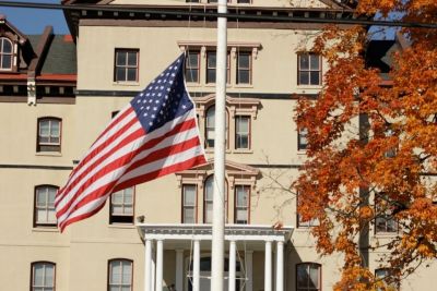 Flag on campus blowing in wind next to autumnal tree