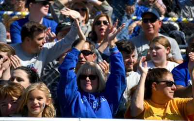 alumni, students, and families cheer in football stands at homecoming