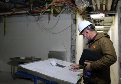 Kevin Kane, wearing hard hat, looks over the schematics of the ACN renovations