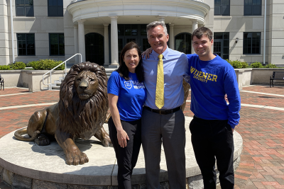 Kristin, Kevin, and Dan Kane pose in front of the Pride lion statues at Widener's Chester Campus