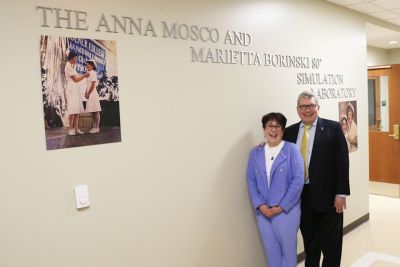 Marietta and Mike Borinki pose for a photo in Founders Hall outside of a newly dedicated simulation lab.