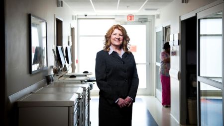 Nursing leader posing in hospital hallway wearing a suit jacket and skirt.