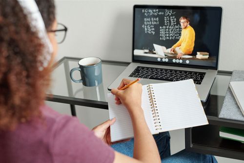 student with notebook in front of laptop