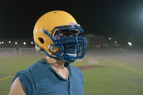 A football players wears the achieve mask under his helmet