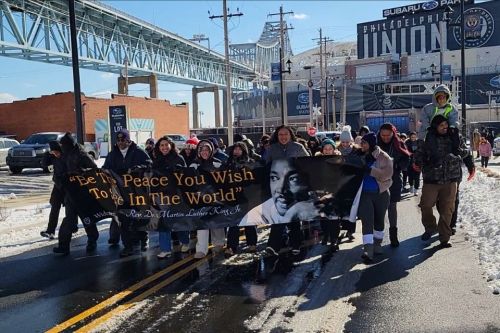 Widener students, community members, and university partners hold a sign and lead the MLK Day of Service peace march outside of the Philadelphia Union stadium.