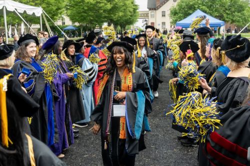 A female graduate student walks through the applause tunnel on her graduation day.