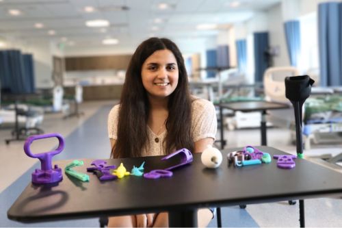 Lydia Aruffo ’25, a recent occupational therapy graduate, sits with a small selection of the 3D printed assistive devices she printed from open-sourced files and customized for clients as part of her capstone project.