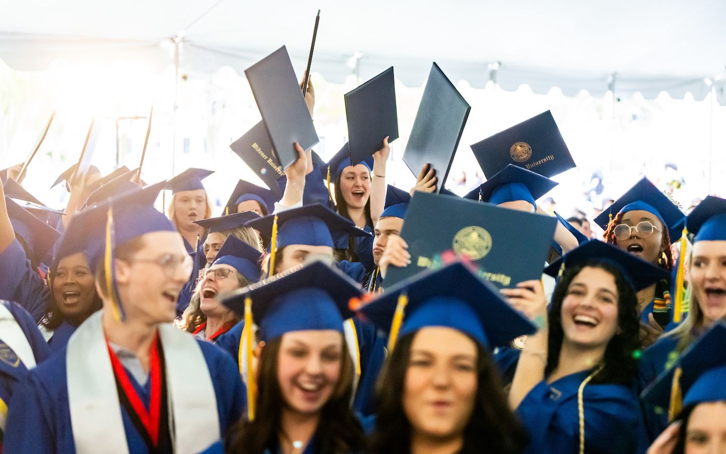 Widener grads at commencement throwing diplomas in air